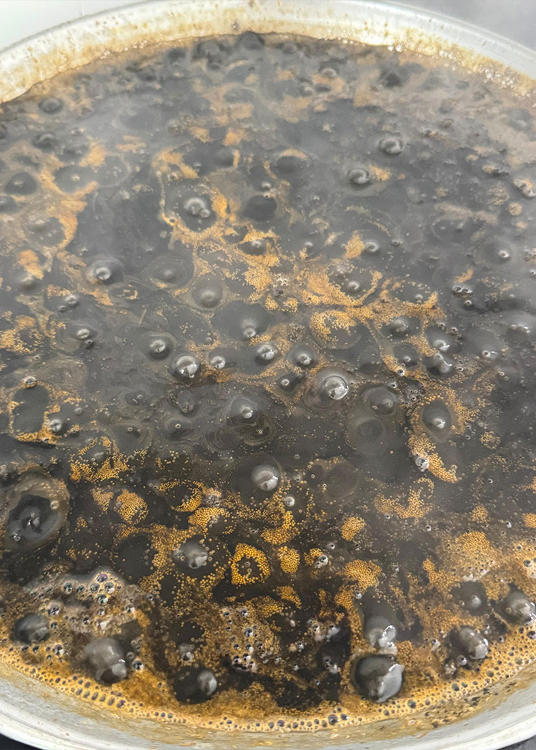 Agregar caldo en paella de arroz negro